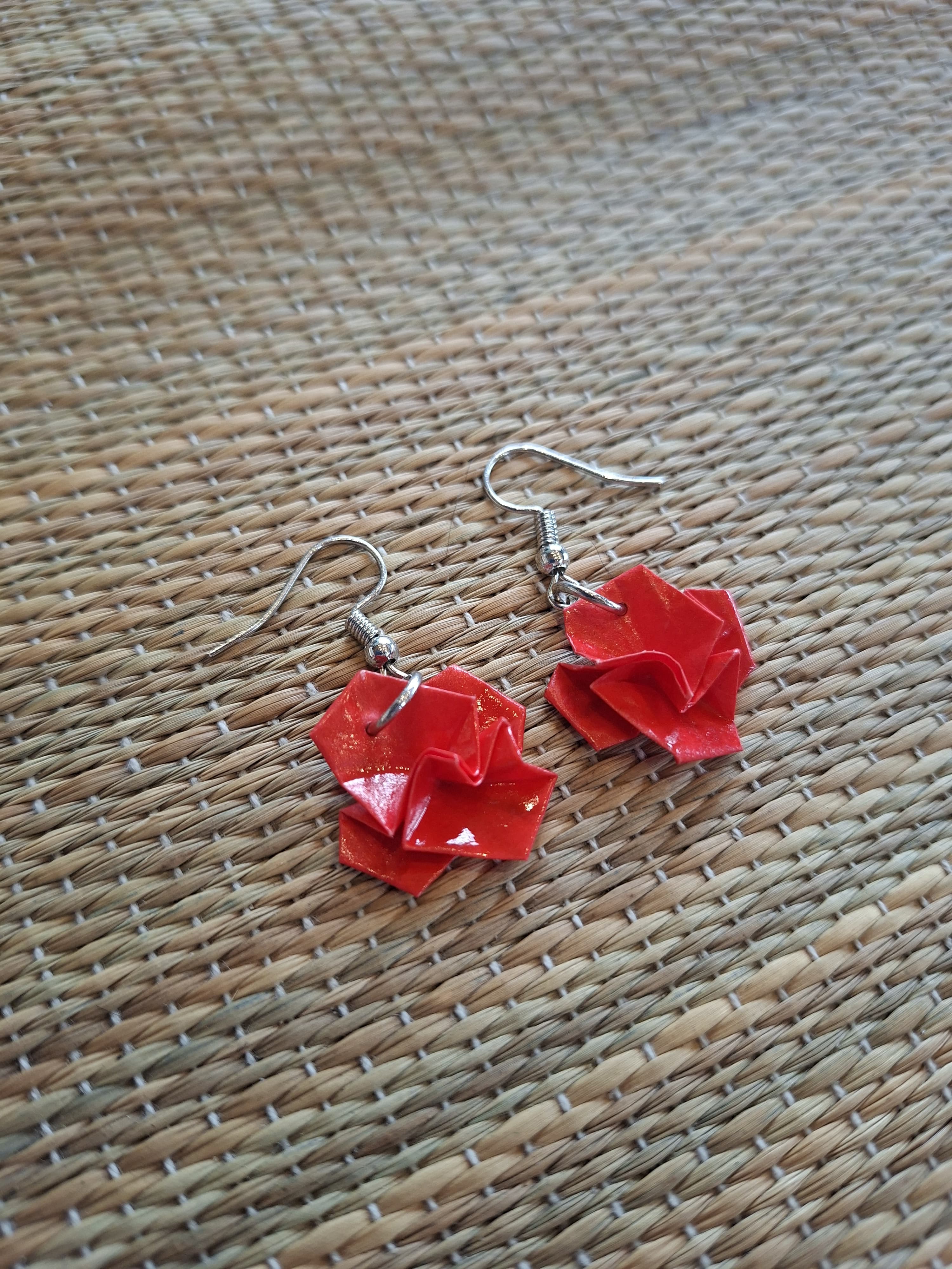 Red origami rose earrings on a woven background